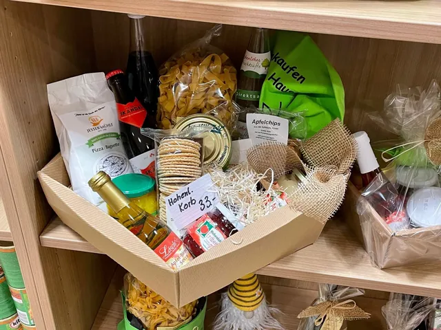 Geöffneter Geschenkkorb mit Nudeln, Wein und Marmelade