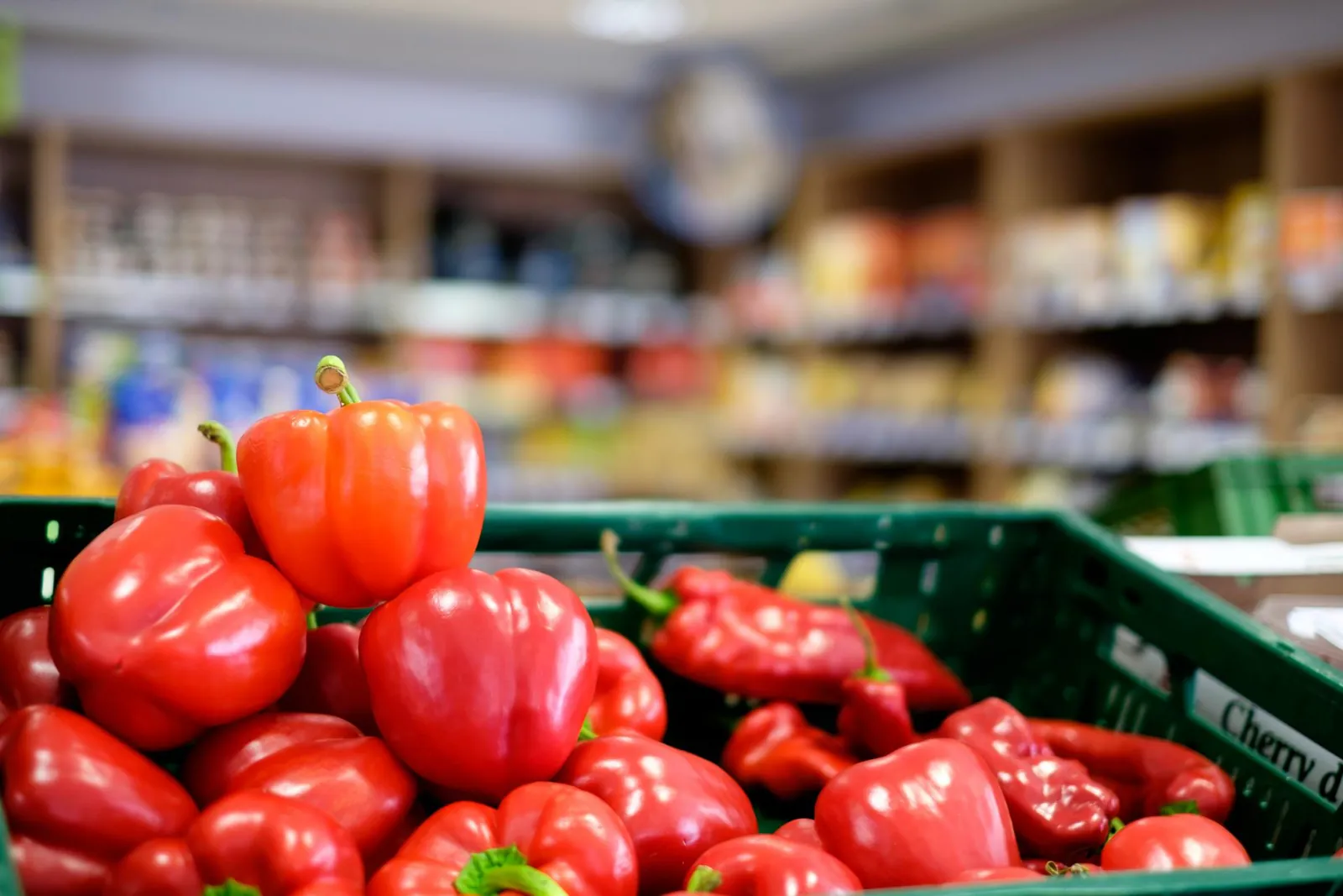 Frische rote Paprika in einer gr&uuml;nen Kiste im Verkaufsraum des L&auml;dle
